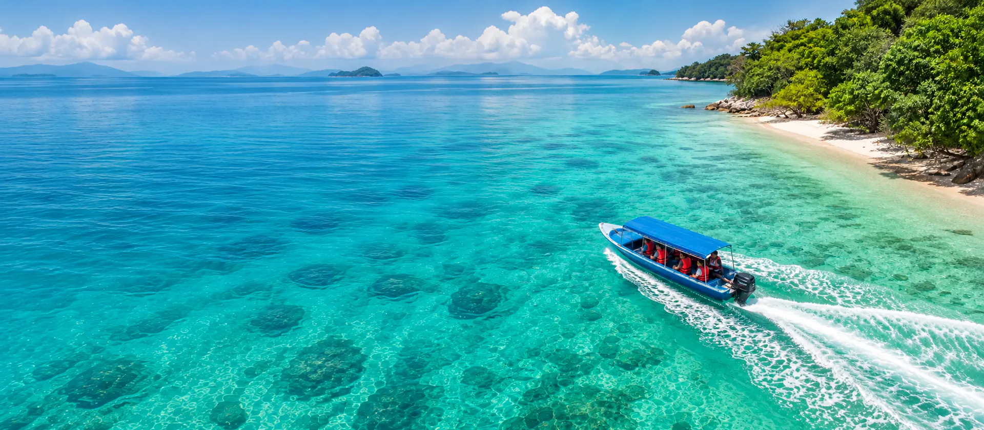Langkawi island-hopping speedboat carrying guests through clear water beside a sandy beach