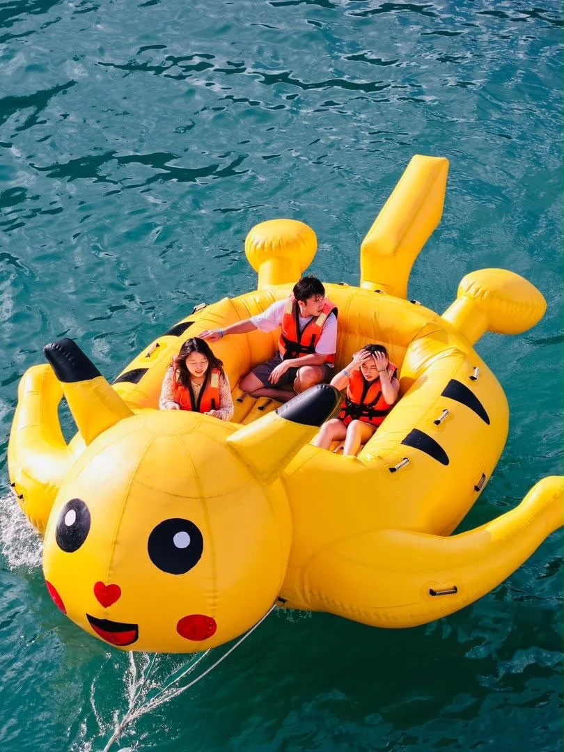 Three guests wearing life jackets on a yellow Pikachu-shaped inflatable